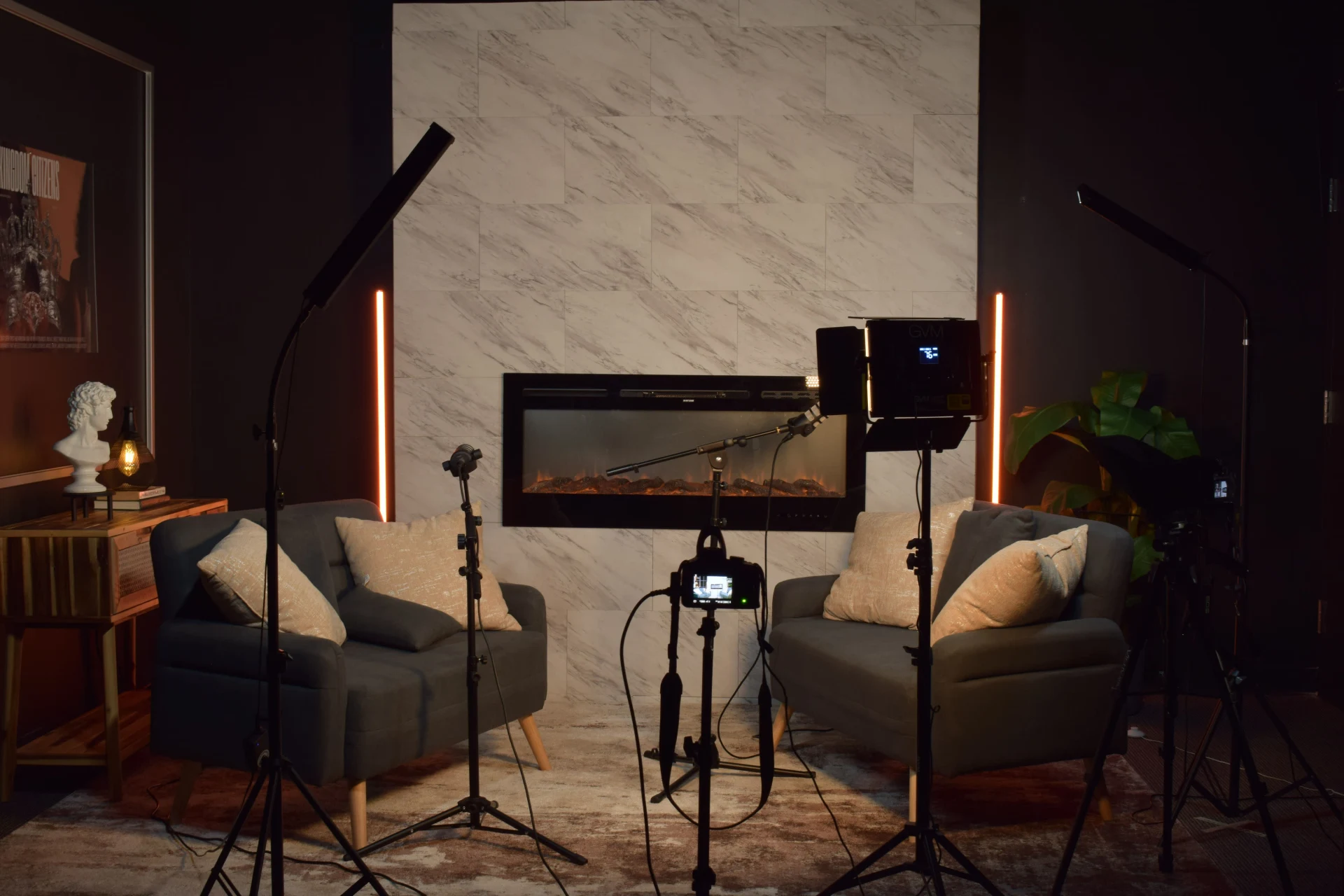 Two-seat podcast set with marble wall, fireplace and warm lighting